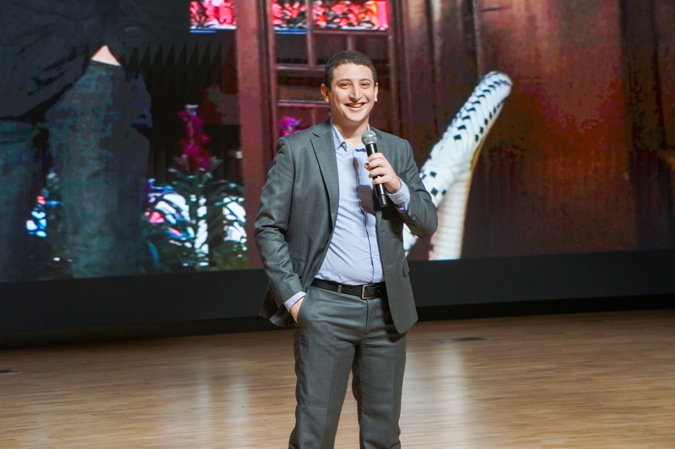 A person in a suit holding a microphone
Description automatically generated