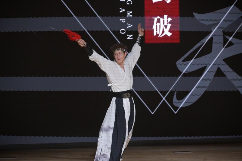 A person in a white and black garment holding a sword
Description automatically generated